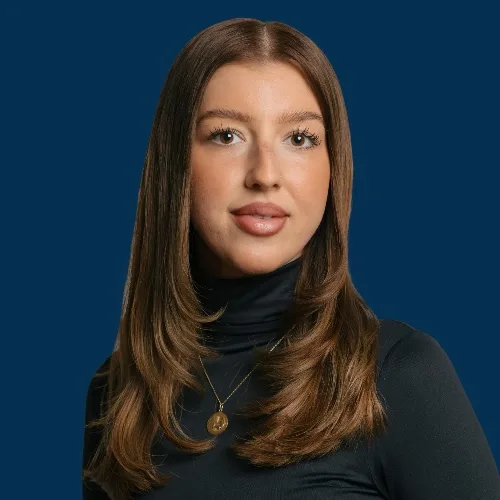 Ardijana vom Aveda Exclusive Salon in Zürich Enge, mit langem braunem Haar, im schwarzen Rollkragen vor dunkelblauem Hintergrund