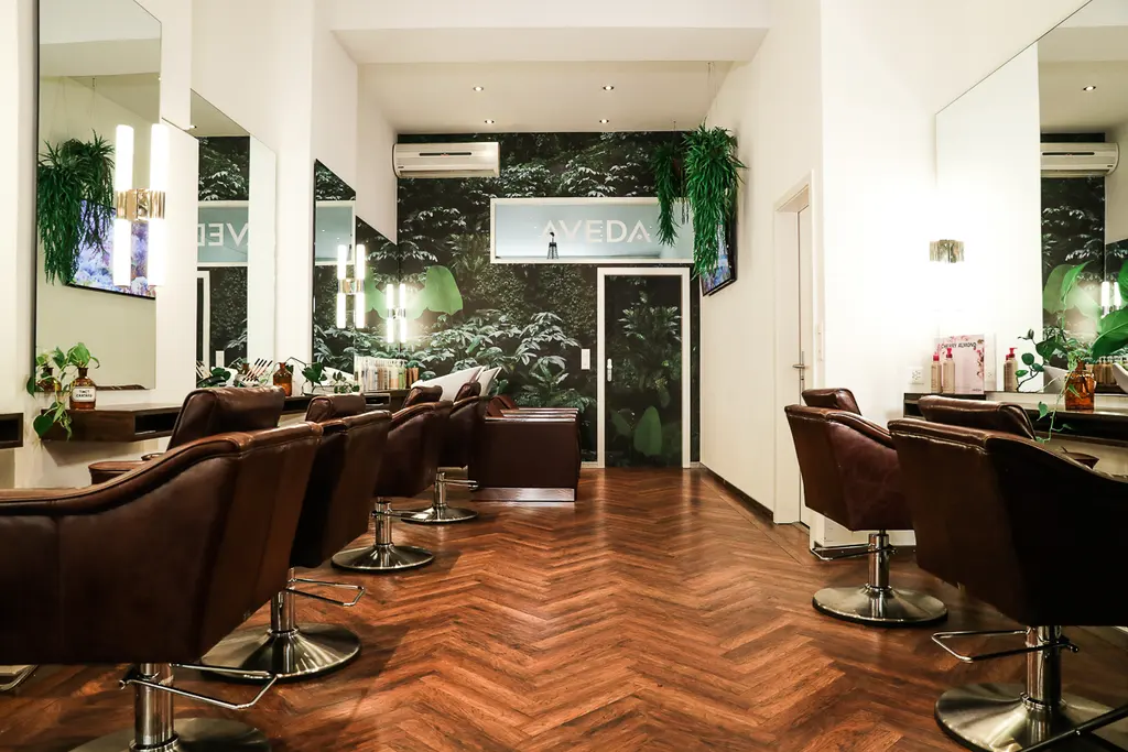 Workstations with leather chairs, herringbone parquet and a plant wall in the Aveda Exclusive Salon by Eddine Belaid in Zurich Enge