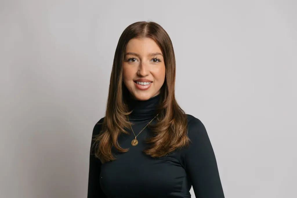 Ardijana, Masterstylistin und Master Coloristin im Aveda Exclusive Salon in Zürich Enge, mit langem braunem Haar, im schwarzen Rollkragen vor hellgrauem Hintergrund